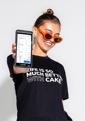A smiling woman holds a CAKEpop handheld POS device in one hand and a CAKE-branded shirt in the other, with the phrase 