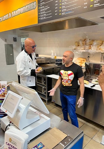 A staff member smiling behind the counter at an Ike's Love and Sandwiches location.