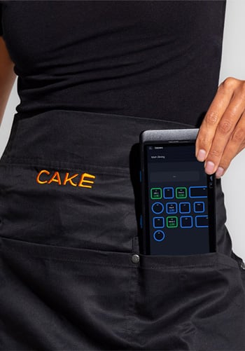A hand reaches into a pocket to pull out a CAKEpop handheld POS device.