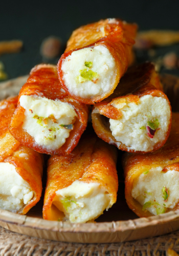 A plate of fried rolls with a creamy filling and a side of sauce