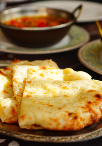 A basket of freshly baked naan bread in an Indian restaurant setting.