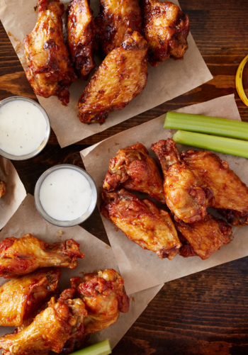 A platter of chicken wings and celery with ranch dipping sauce.