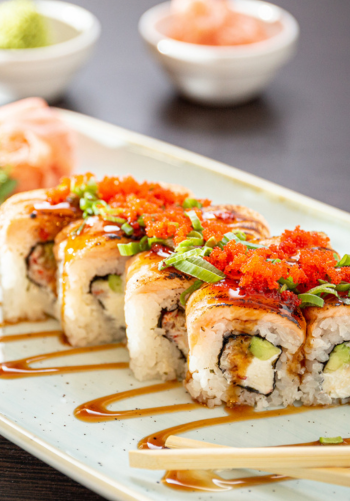 A plate of sushi rolls topped with fish roe and a drizzle of sauce.