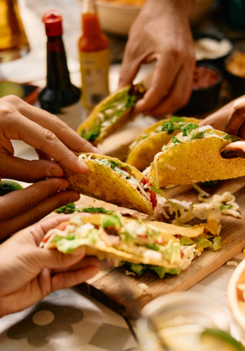 A hand holding a taco with meat and fresh toppings.